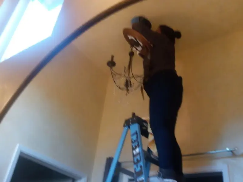 Electrician installing a chandelier in a Blue Ash residence